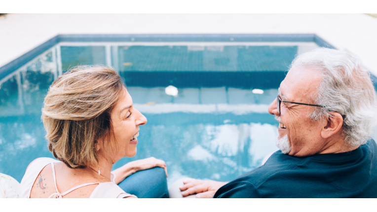 Couple smiling at each other by the pool.